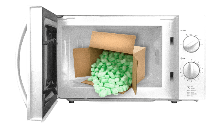 An open microwave with a box of polystyrene packing peanuts in it