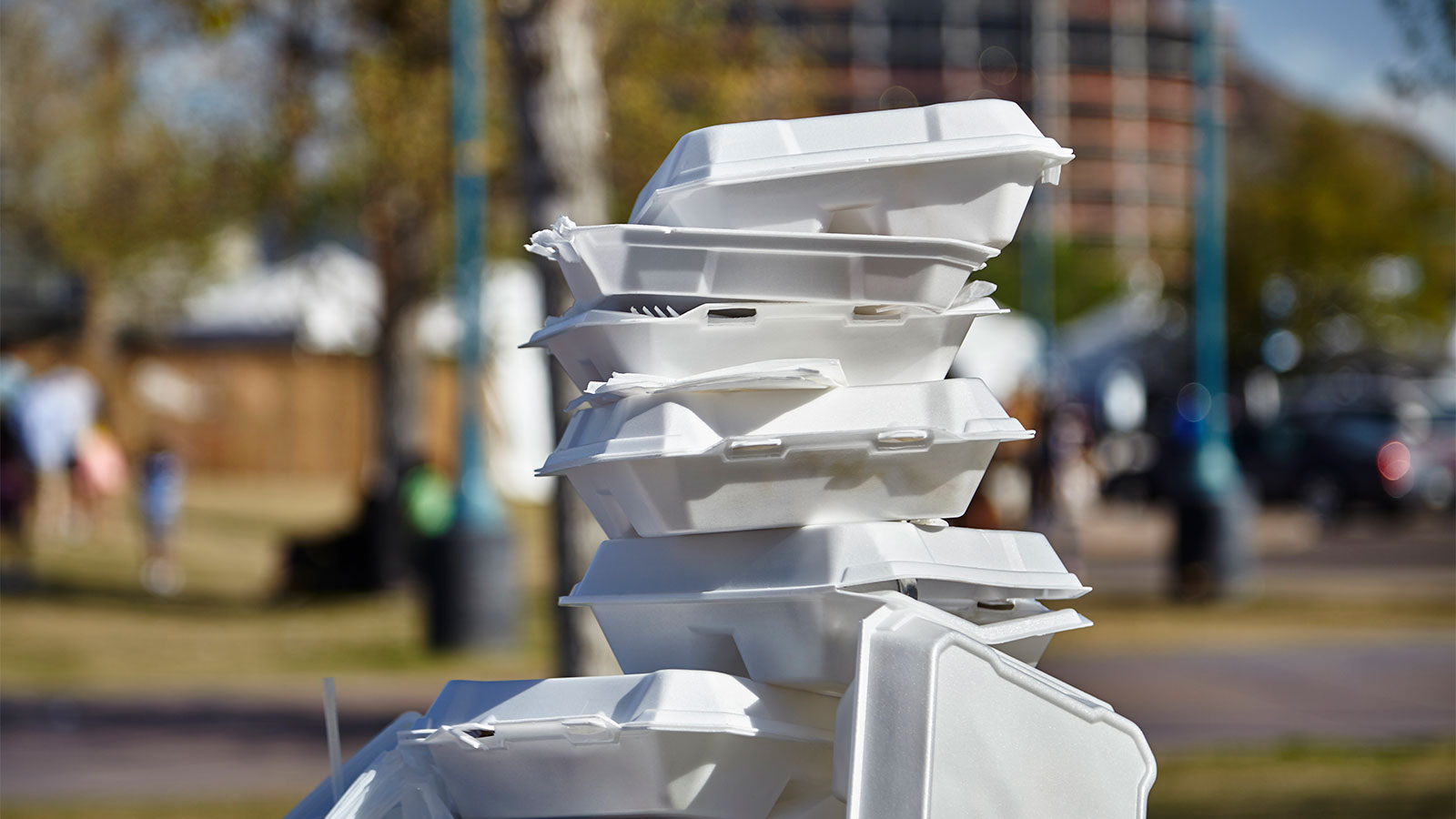 A pile of styrofoam containers piled on a trash can