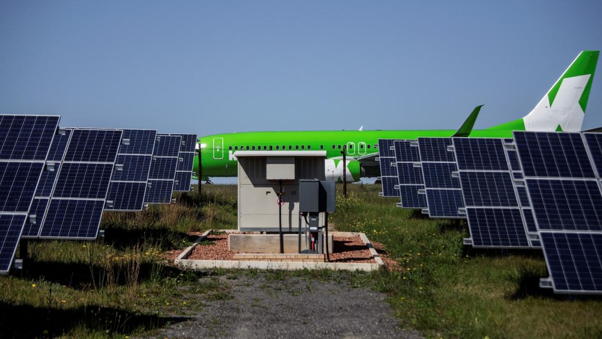 green airplane behind solar panels