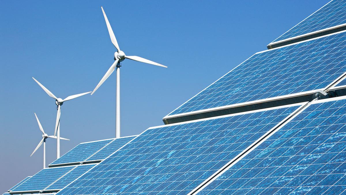 Photograph of solar panels with wind turbines in the background