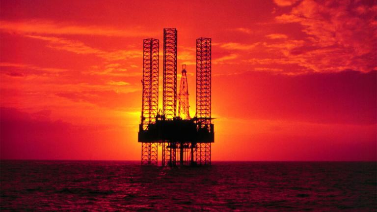 An offshore oil rig against a brilliant sunset