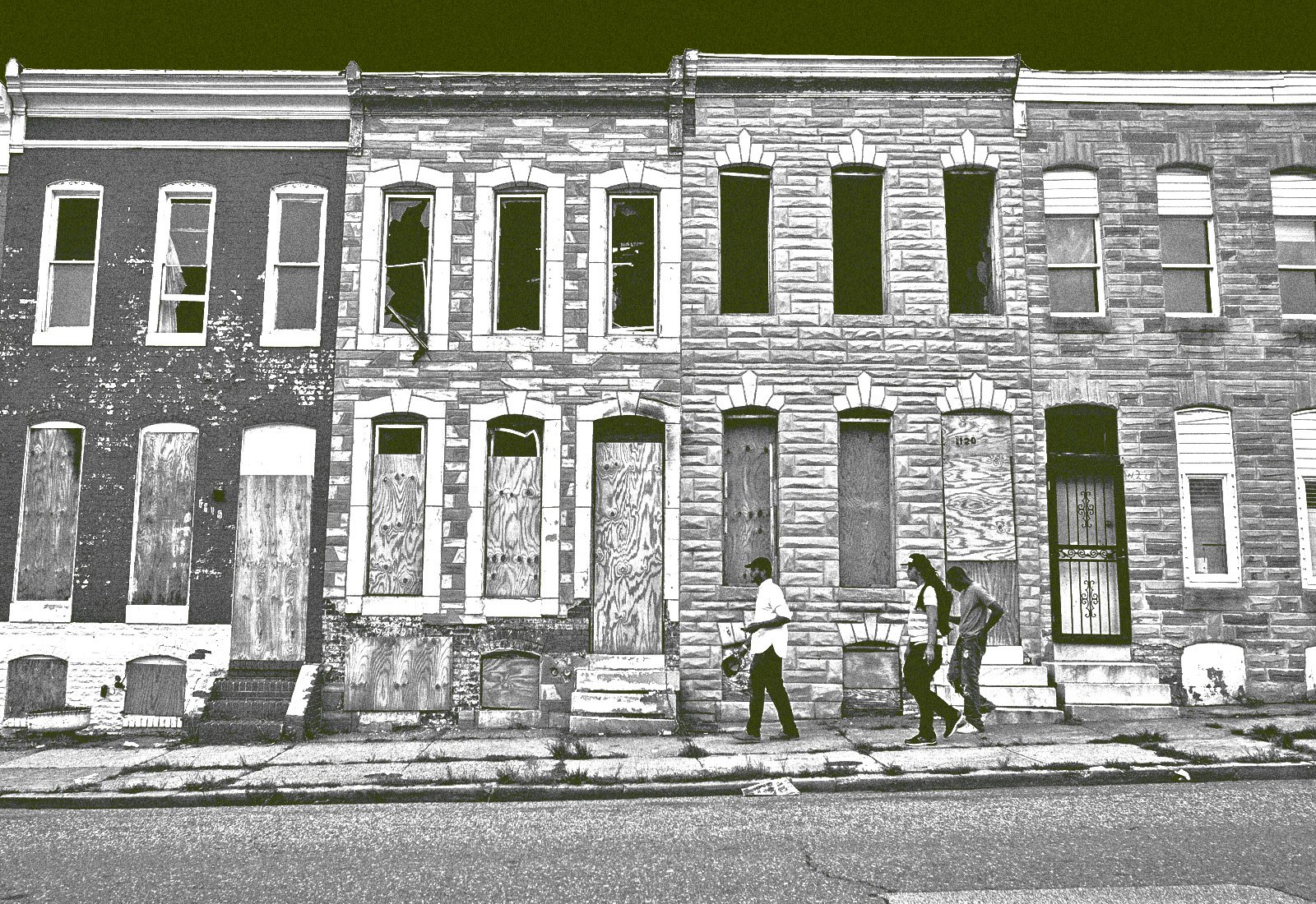 Three pedestrians pass by a row of boarded up houses in east Baltimore, Maryland.
