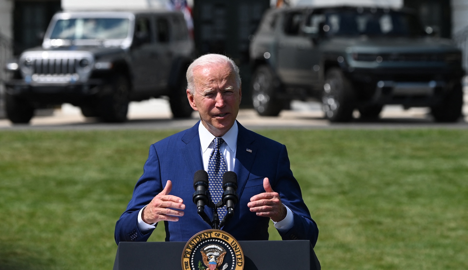 Biden stands in front of two electric vehicles.