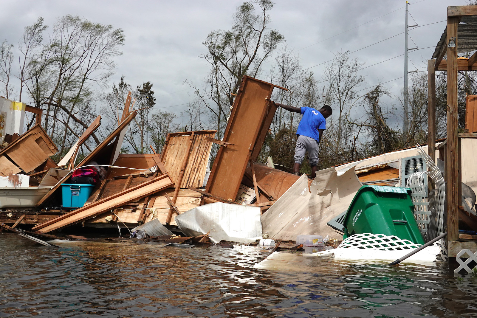A man stands on top of a pile of furniture and home furnishings destroyed during Hurricane Ida.