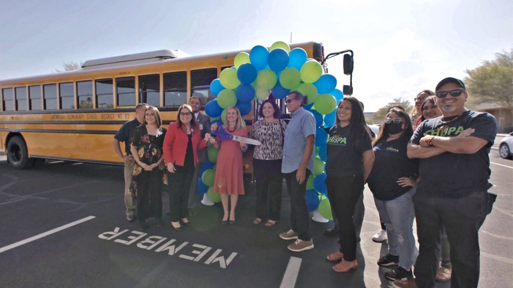 Group of people with balloons standing in front of a school bus