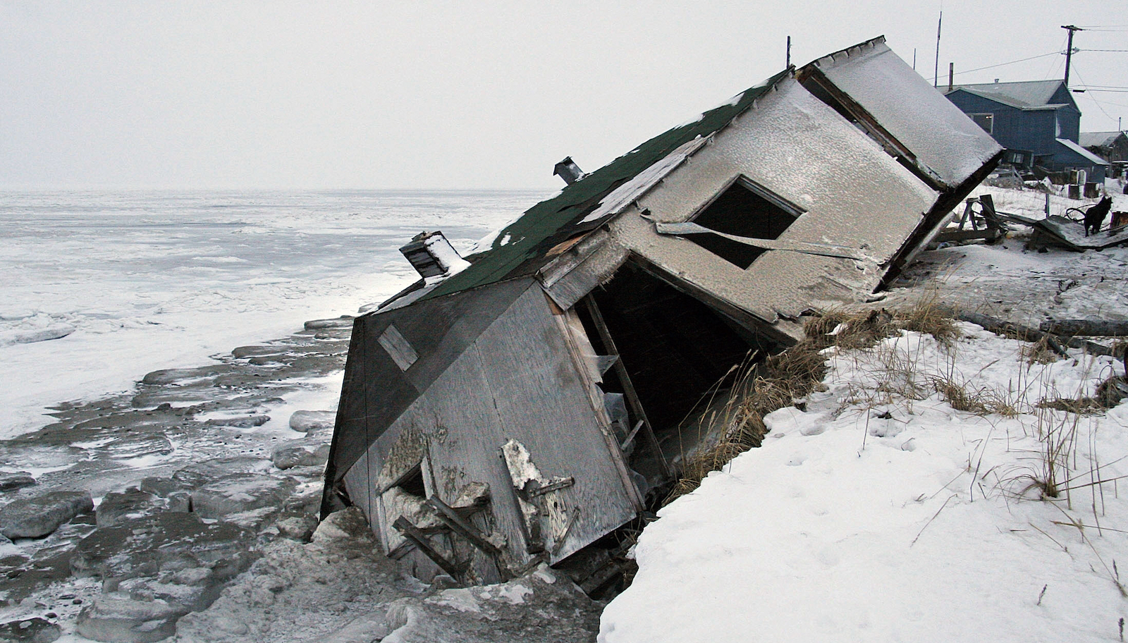 An abandoned house collapses into the water due to coastal erosion in Alaska.
