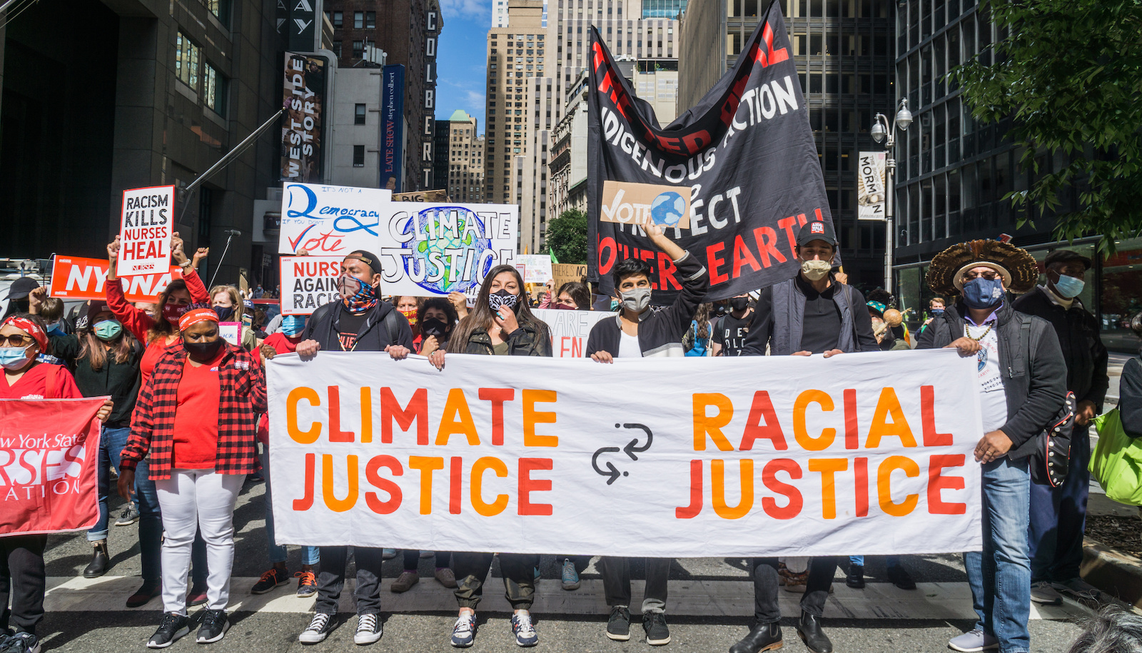protestors hold a banner that says climate justice equals racial justice