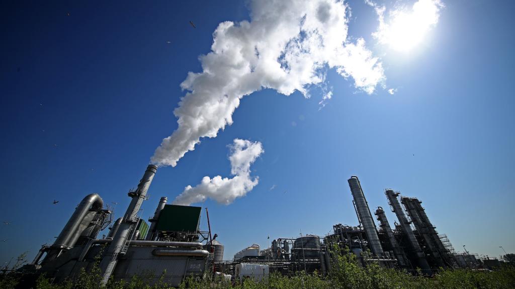 An oil refinery billows smoke.