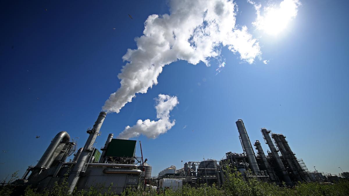 An oil refinery billows smoke.