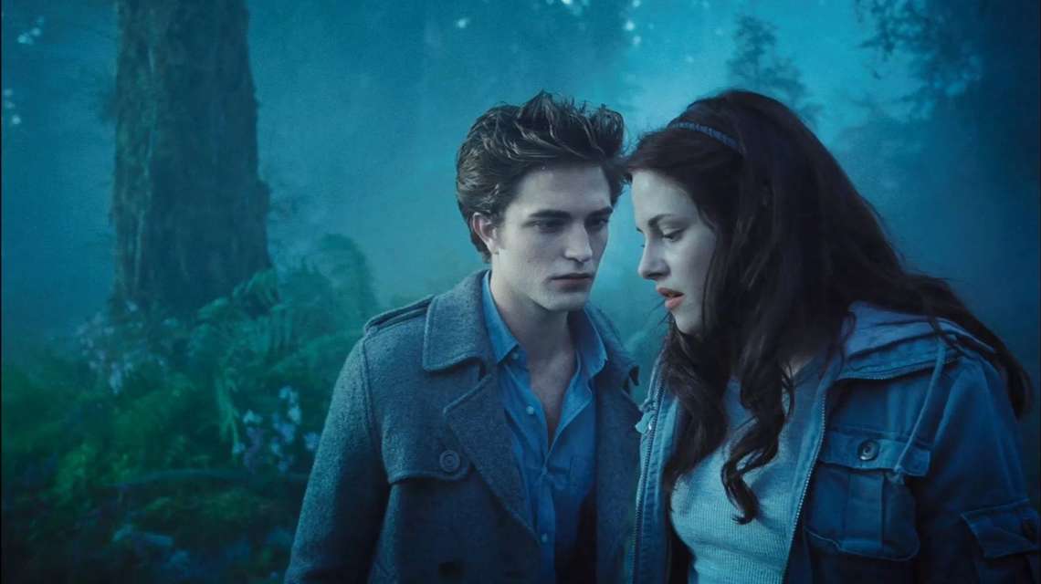 a photo still from the movie Twilight with a foggy blue tree background and Edward and Bella in the foreground