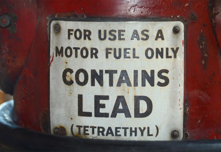 A vintage gasoline sign that reads "For use as a motor fuel only. Contains lead (tetraethyl)"