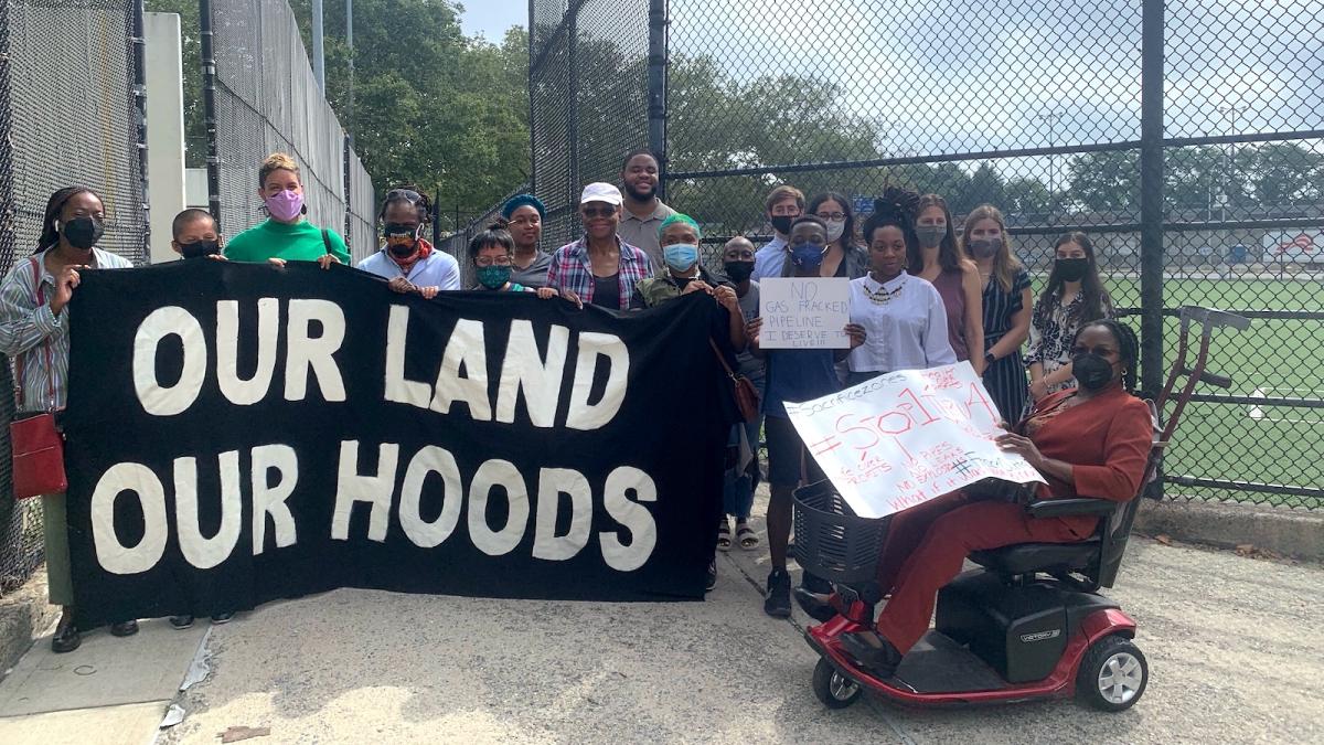 Community organizers with a sign reading, "Our land, our hoods."