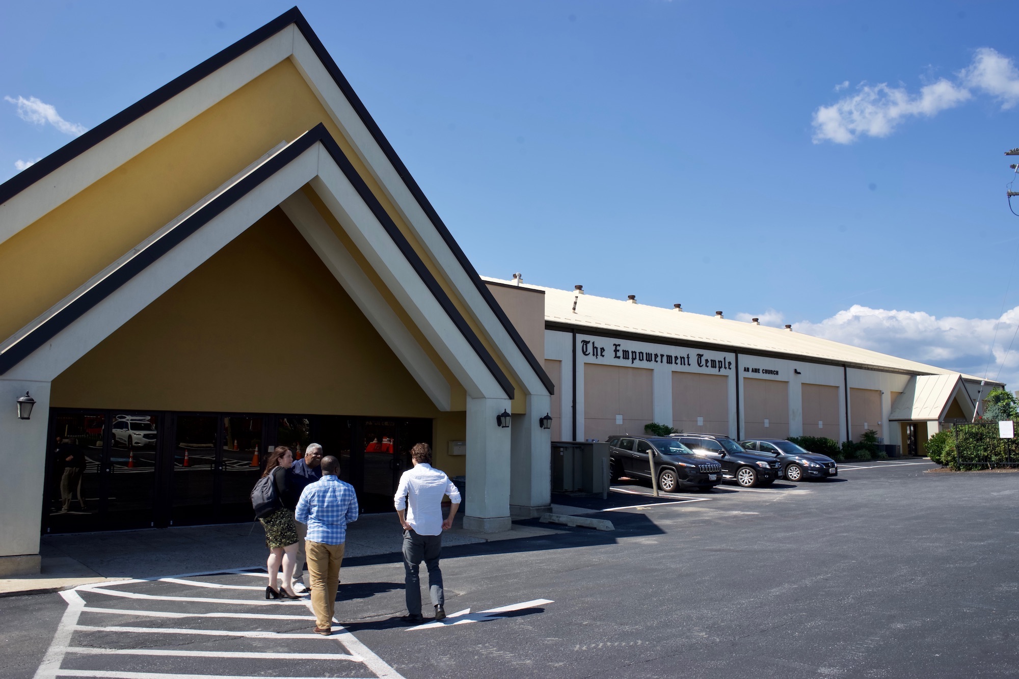 A large angled arch of a building in front of a large parking lot. On the body of the building it reads 