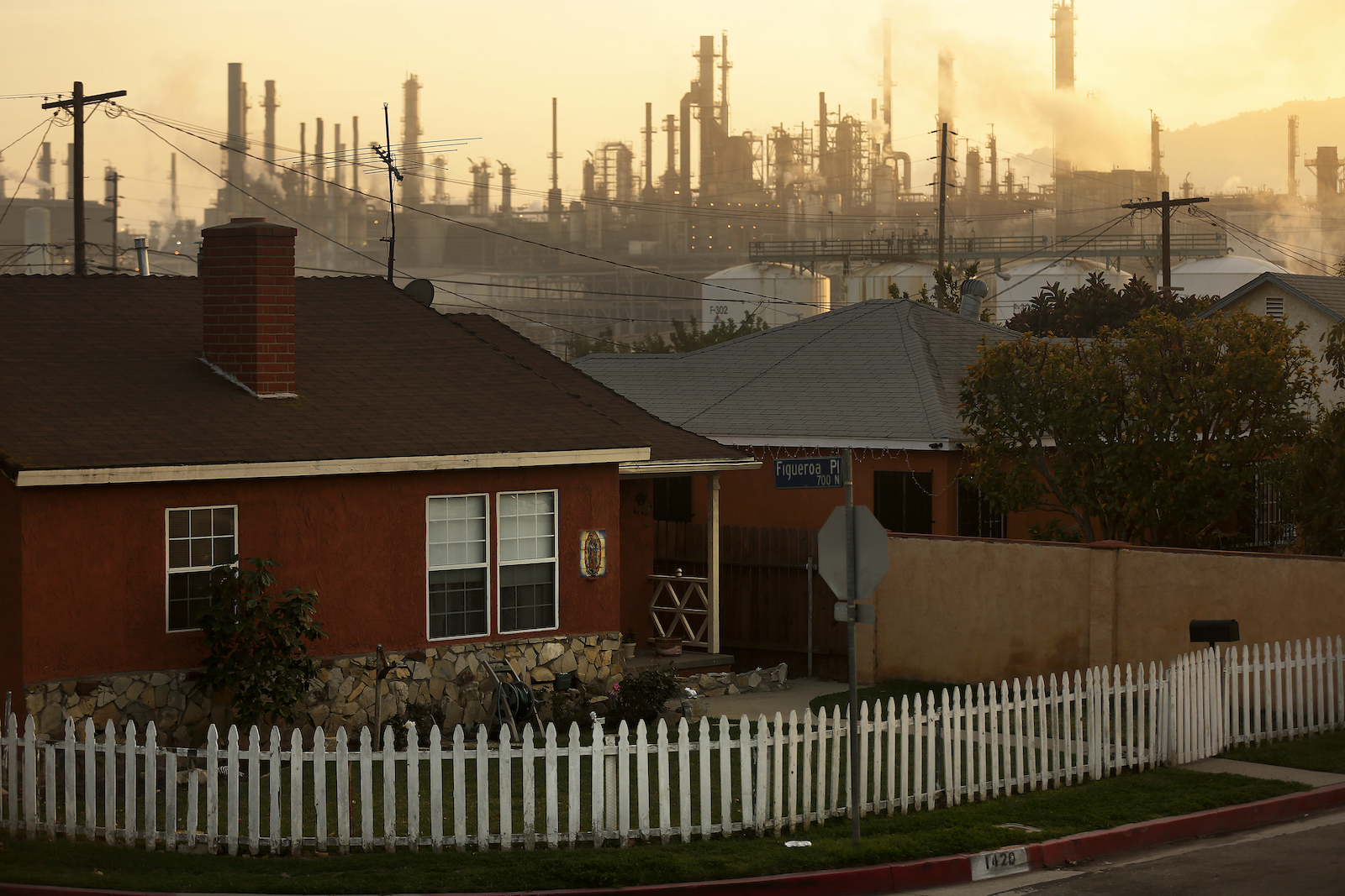 A sprawling refinery in the background of a row of residential homes.