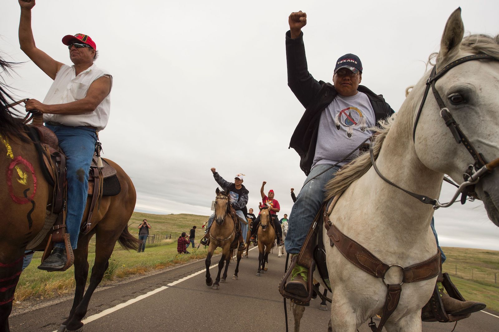 Indigenous activists on horseback raise their fists in protest
