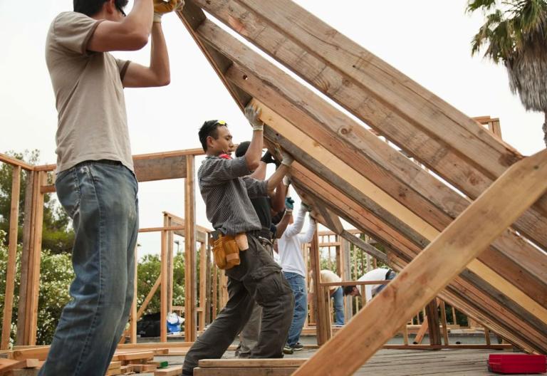 Construction workers lifting house frame