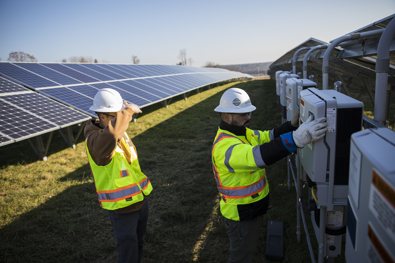 Employees from a Radian Generation's operations and maintenance team change out a faulty solar inverter along a row of solar panels December 4, 2017 in Oxford, Massachusetts. The 16.5 megawatt solar array, on what was once the largest pig farm in the northeast, is owned and operated by BlueWave Solar which feeds the generated electricity to homes and small businesses and to the Fay School and Phillips Academy Andover private schools.