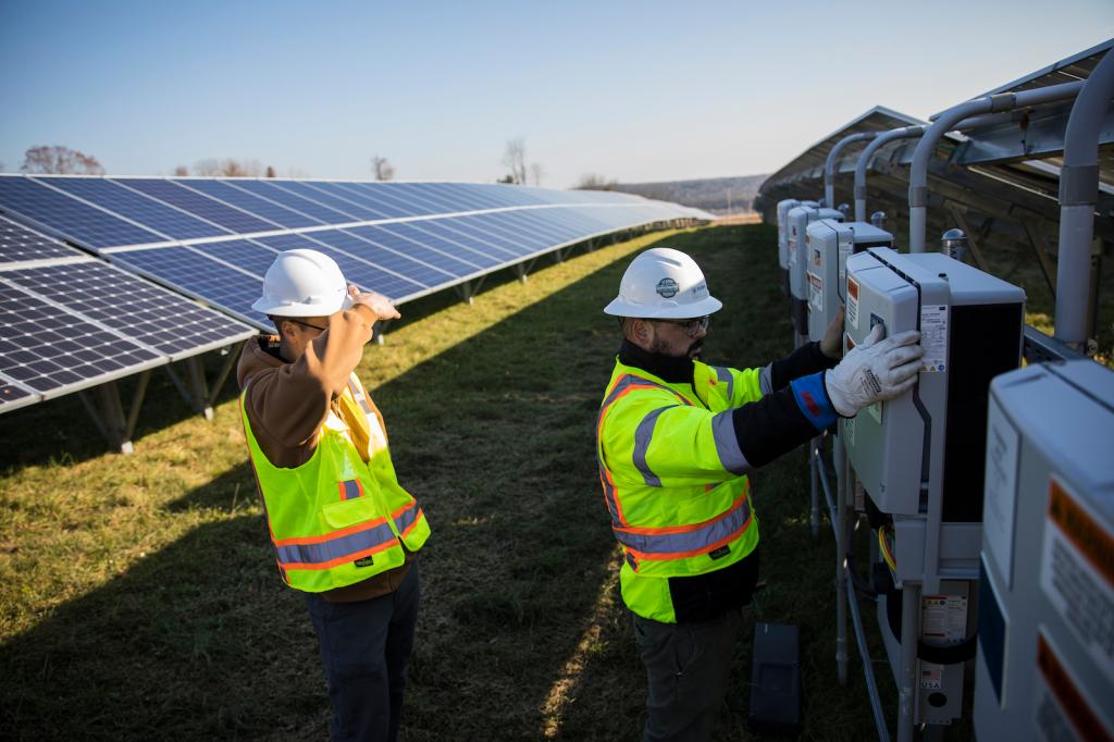 Employees from a Radian Generation's operations and maintenance team change out a faulty solar inverter along a row of solar panels December 4, 2017 in Oxford, Massachusetts. The 16.5 megawatt solar array, on what was once the largest pig farm in the northeast, is owned and operated by BlueWave Solar which feeds the generated electricity to homes and small businesses and to the Fay School and Phillips Academy Andover private schools.