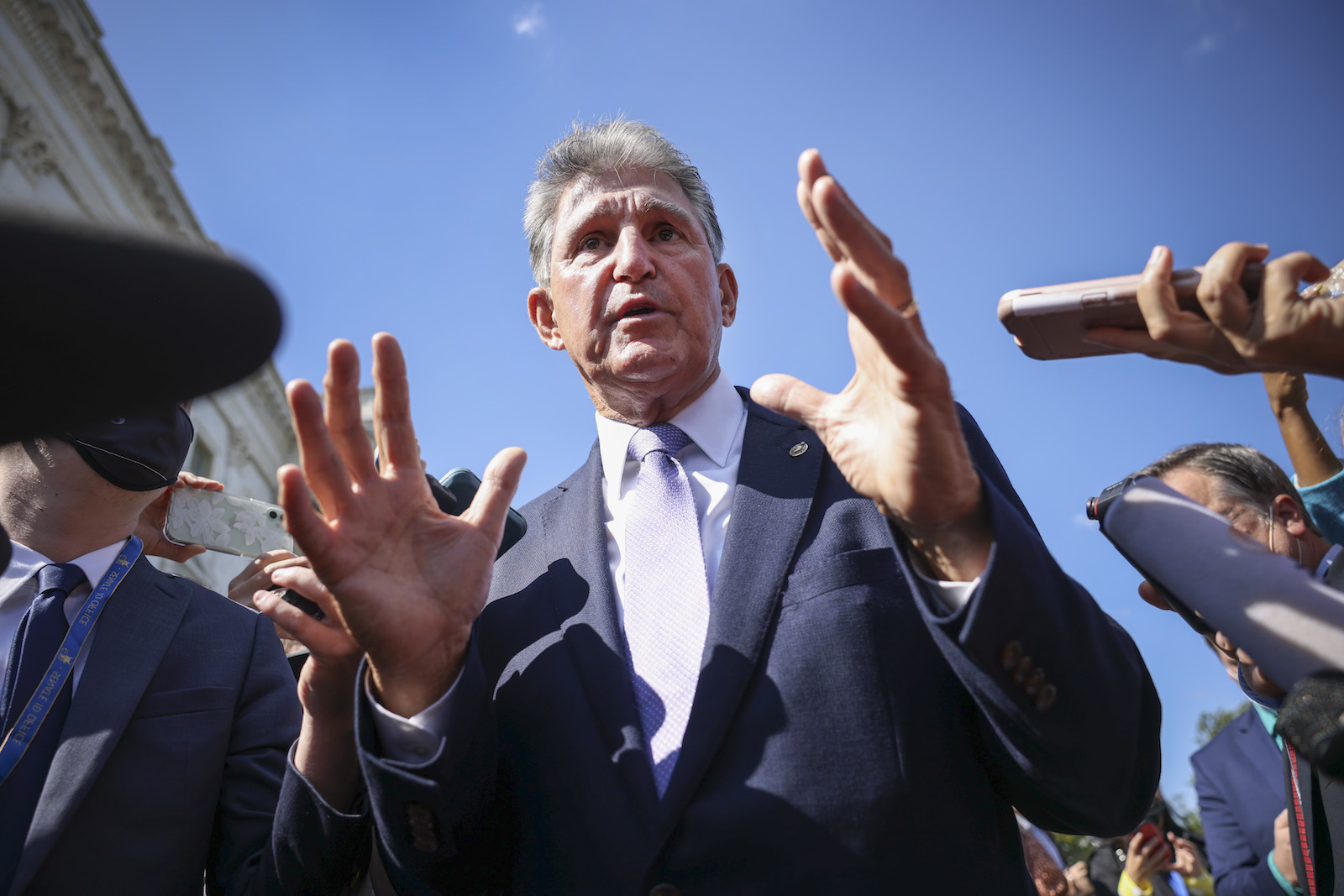 joe manchin holds up his hands as he speaks to a crowd of reporters