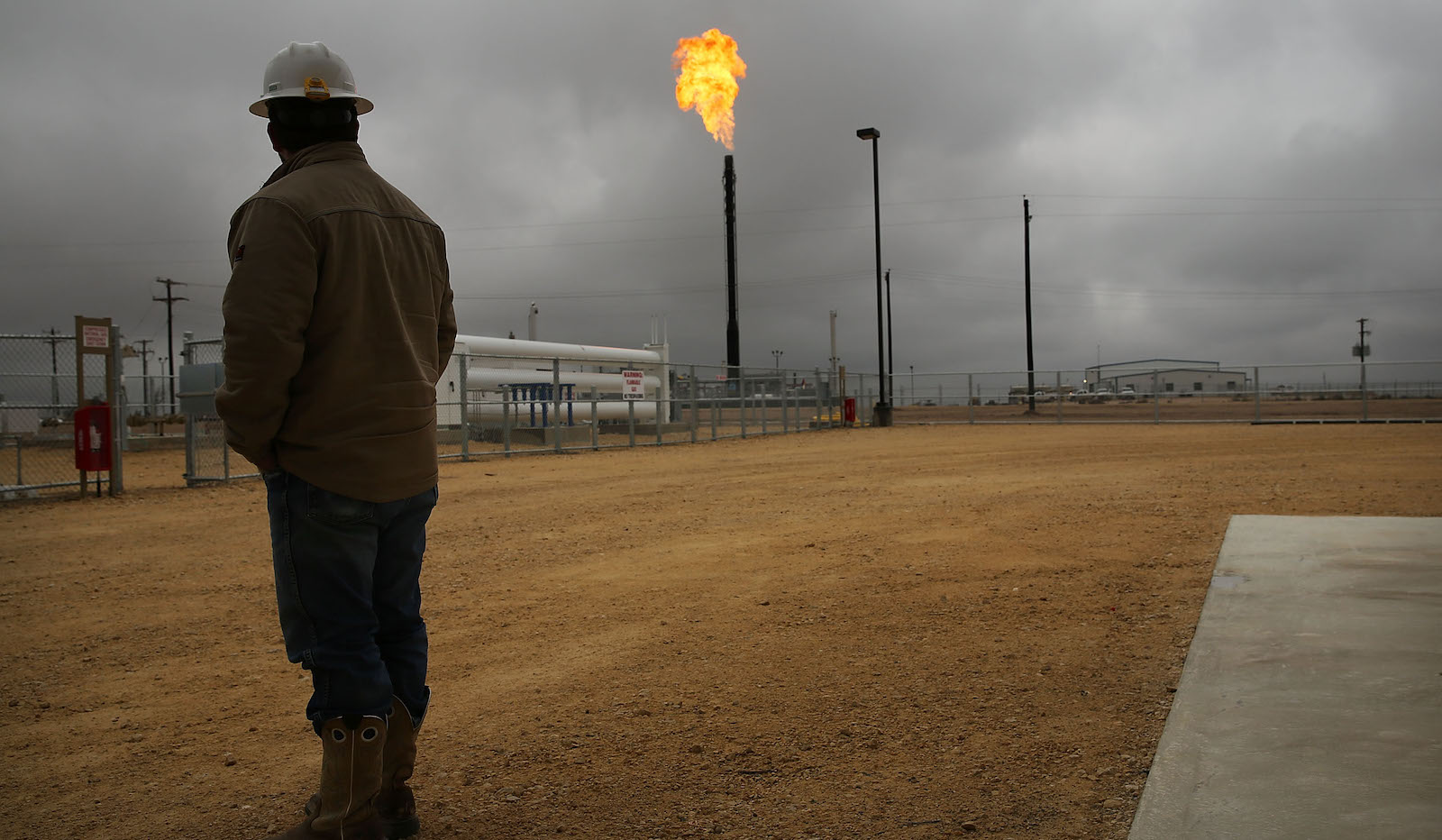 texas oil worker stares at gas flare