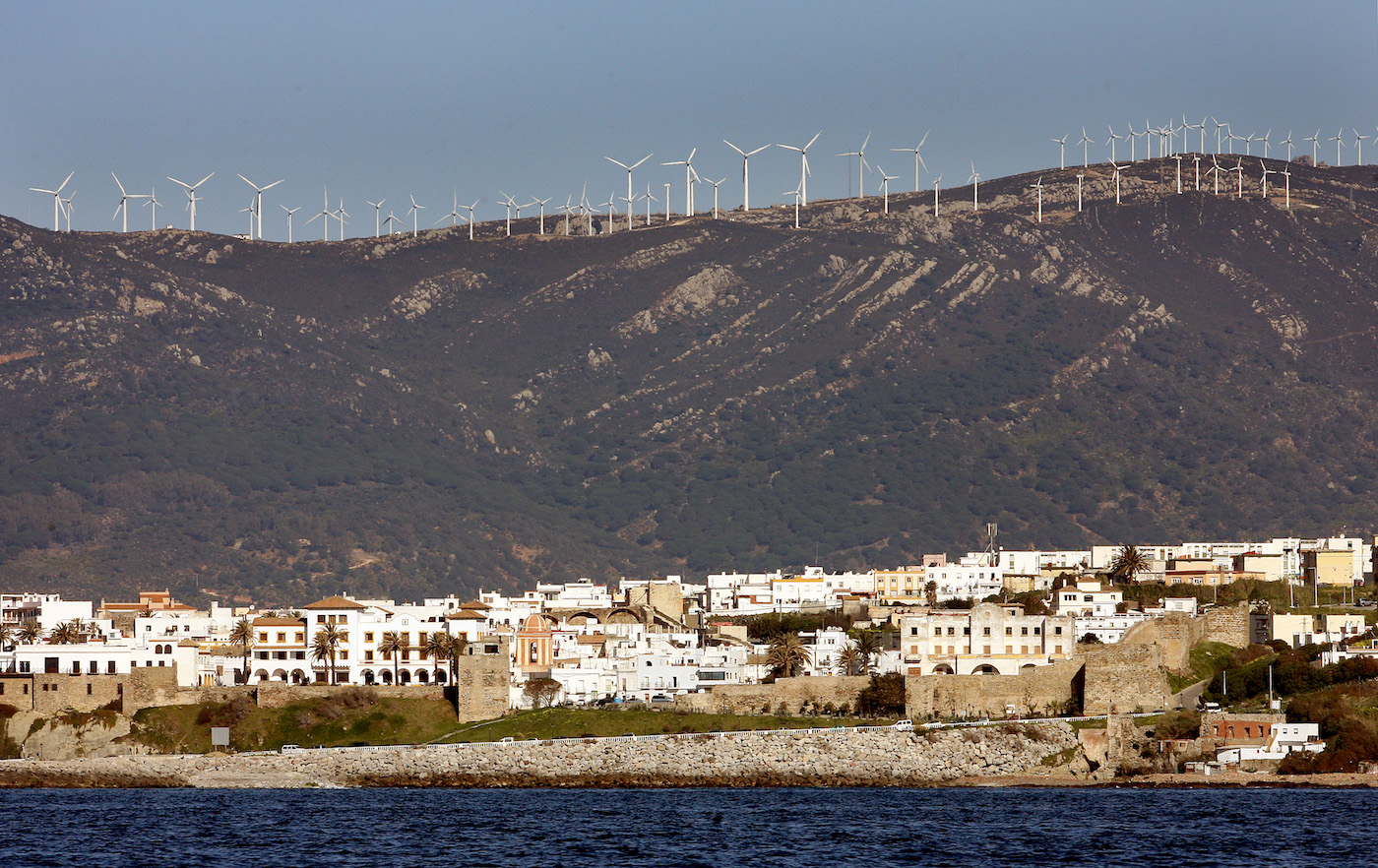 Wind turbines line a hill above a city in southern Spain