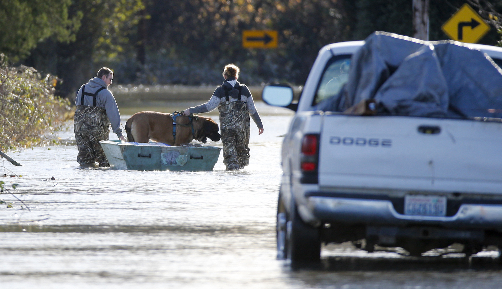 A man and woman ferry a dog down a flooded Sterling Road in Sedro-Woolley, Washington, on November 17, 2021.
