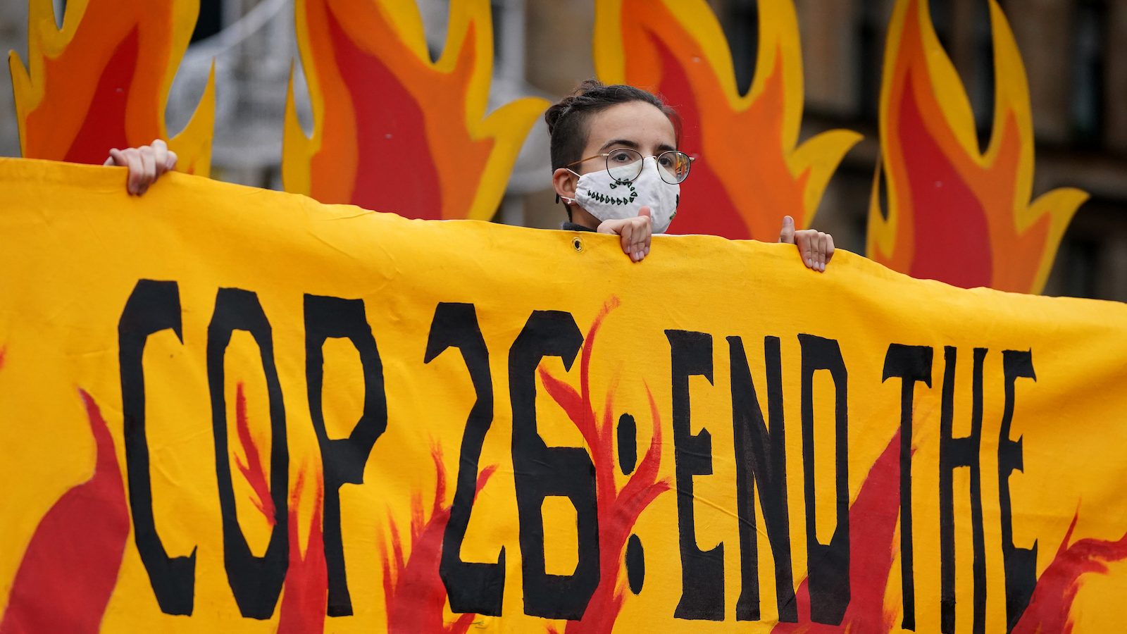 A climate protester holds a sign with orange flames at COP26.