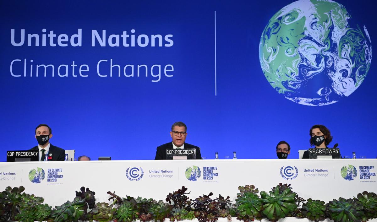 The leaders of COP26 sit behind a large table at the annual U.N. climate conference.