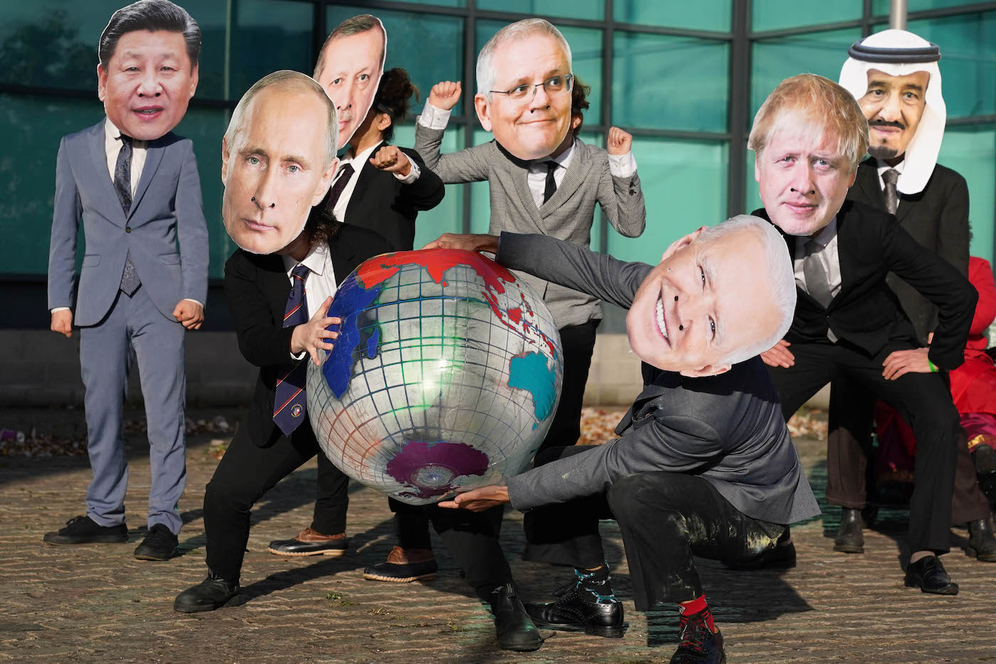 Activists in costume as world leaders hold a beach ball globe