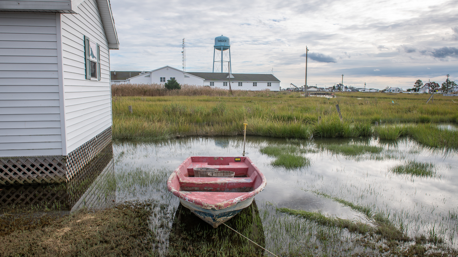 A boat parked in water behind a house on Tangier Island.