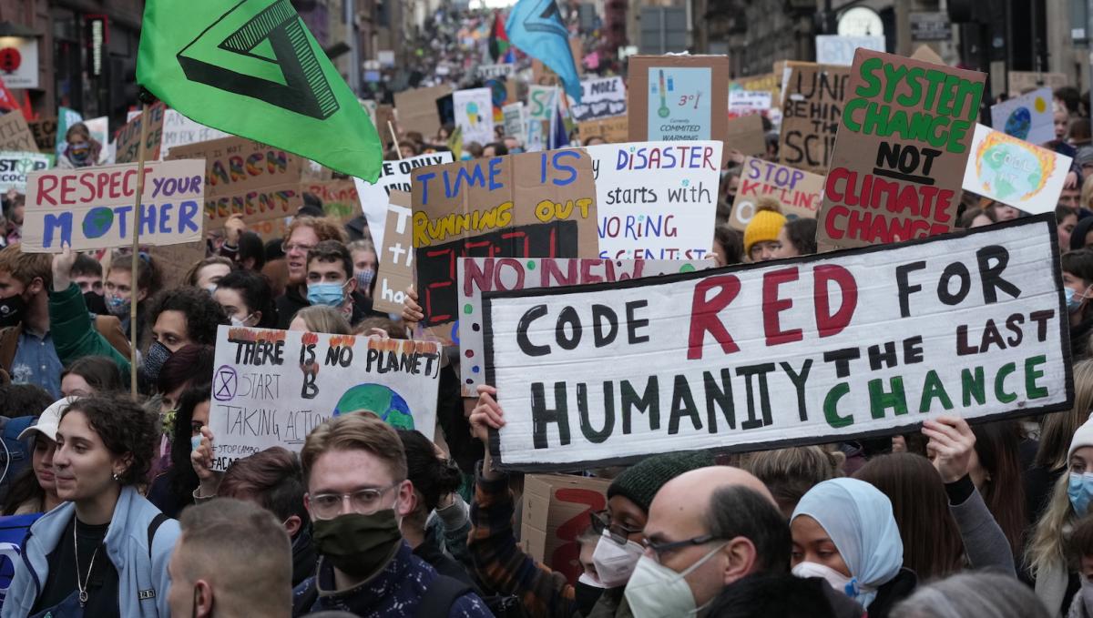 A crowd of Fridays for Future protesters in Glasgow Scotland during Cop26 featuring a sign that says "code red for humanity"