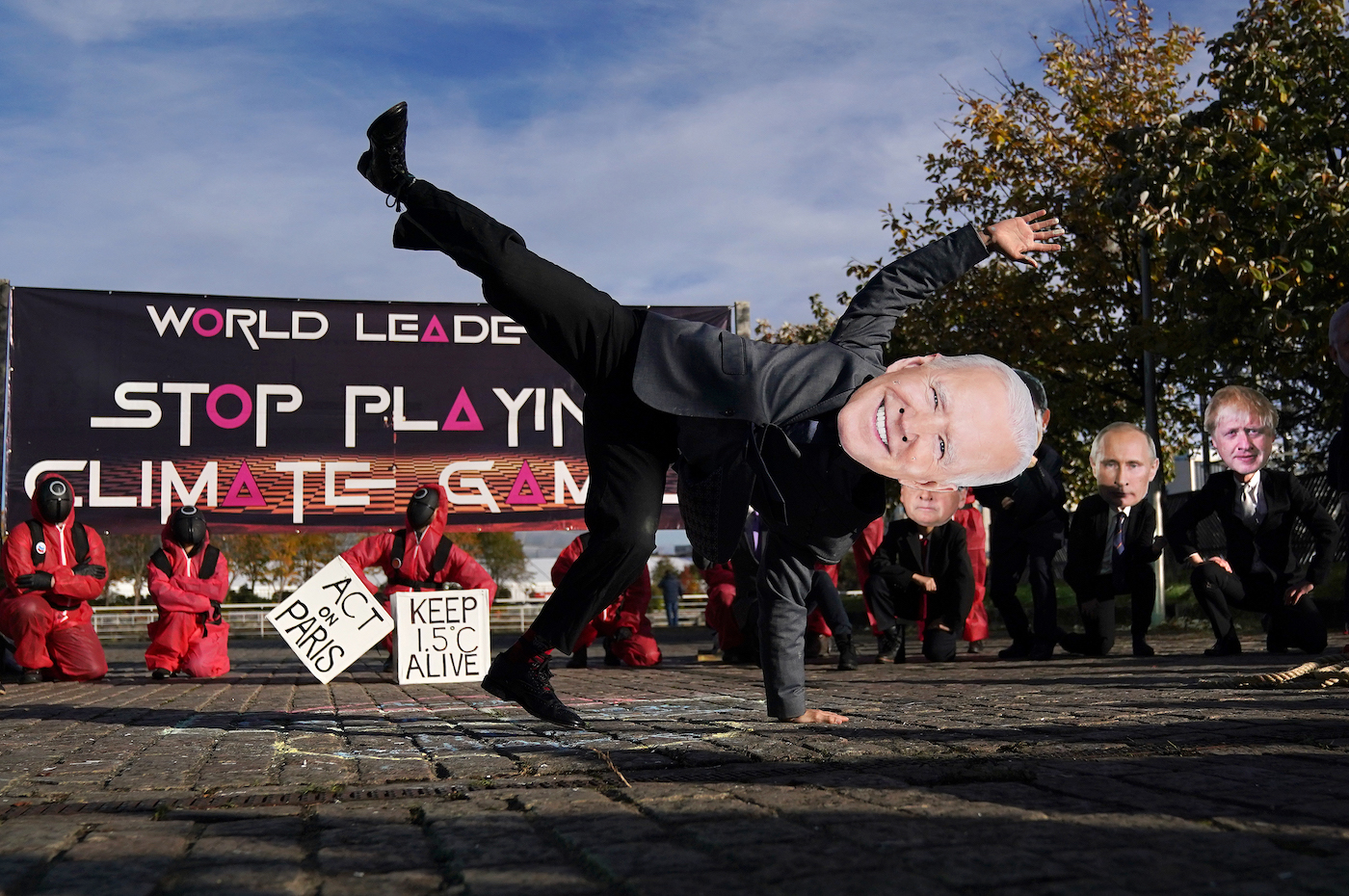 Activist dressed as Joe Biden breakdances in front of a line of protesters