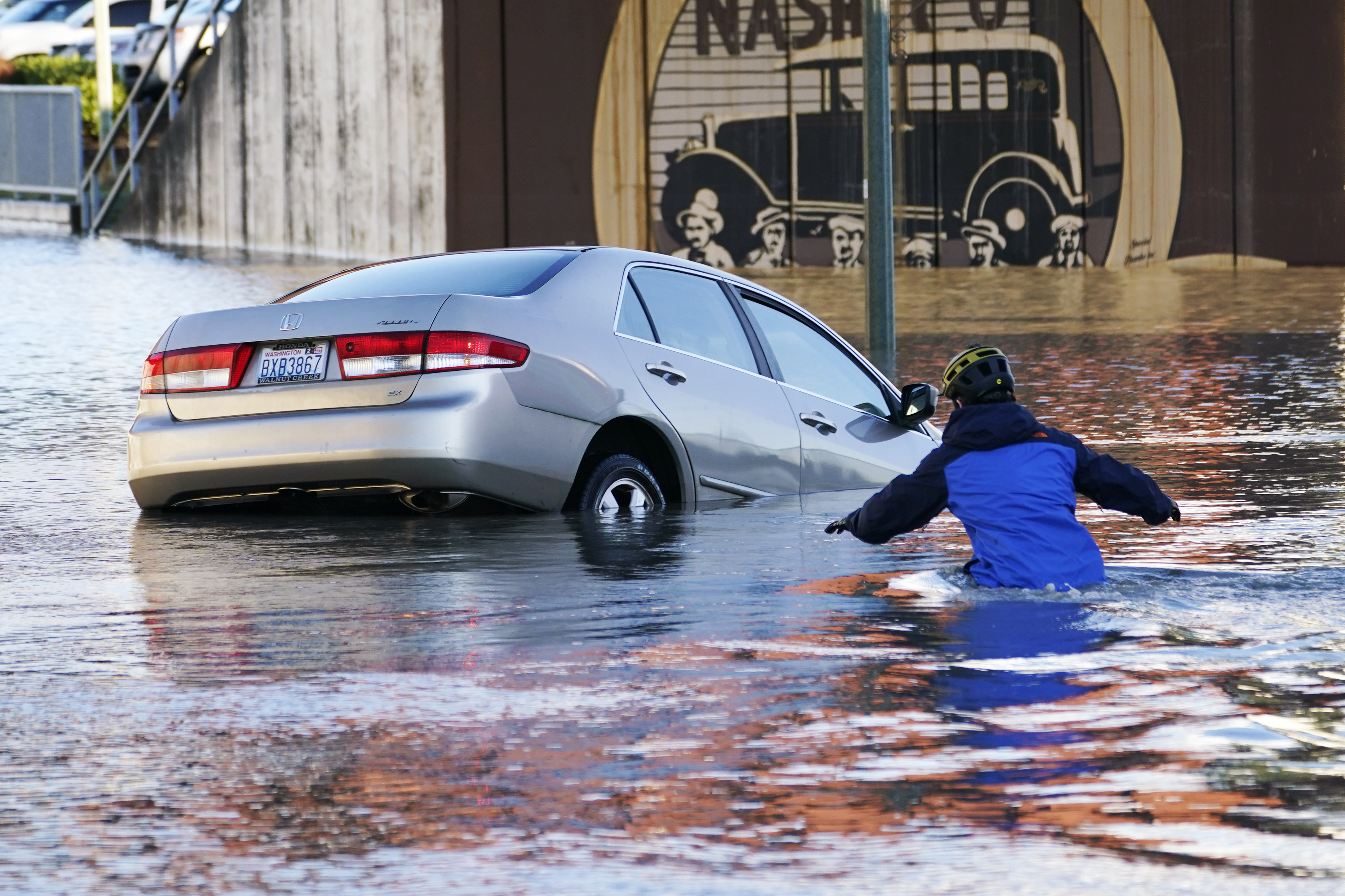 A man wades into the water to help rescue a flooded car in the Nooksack River in Ferndale, Washington.