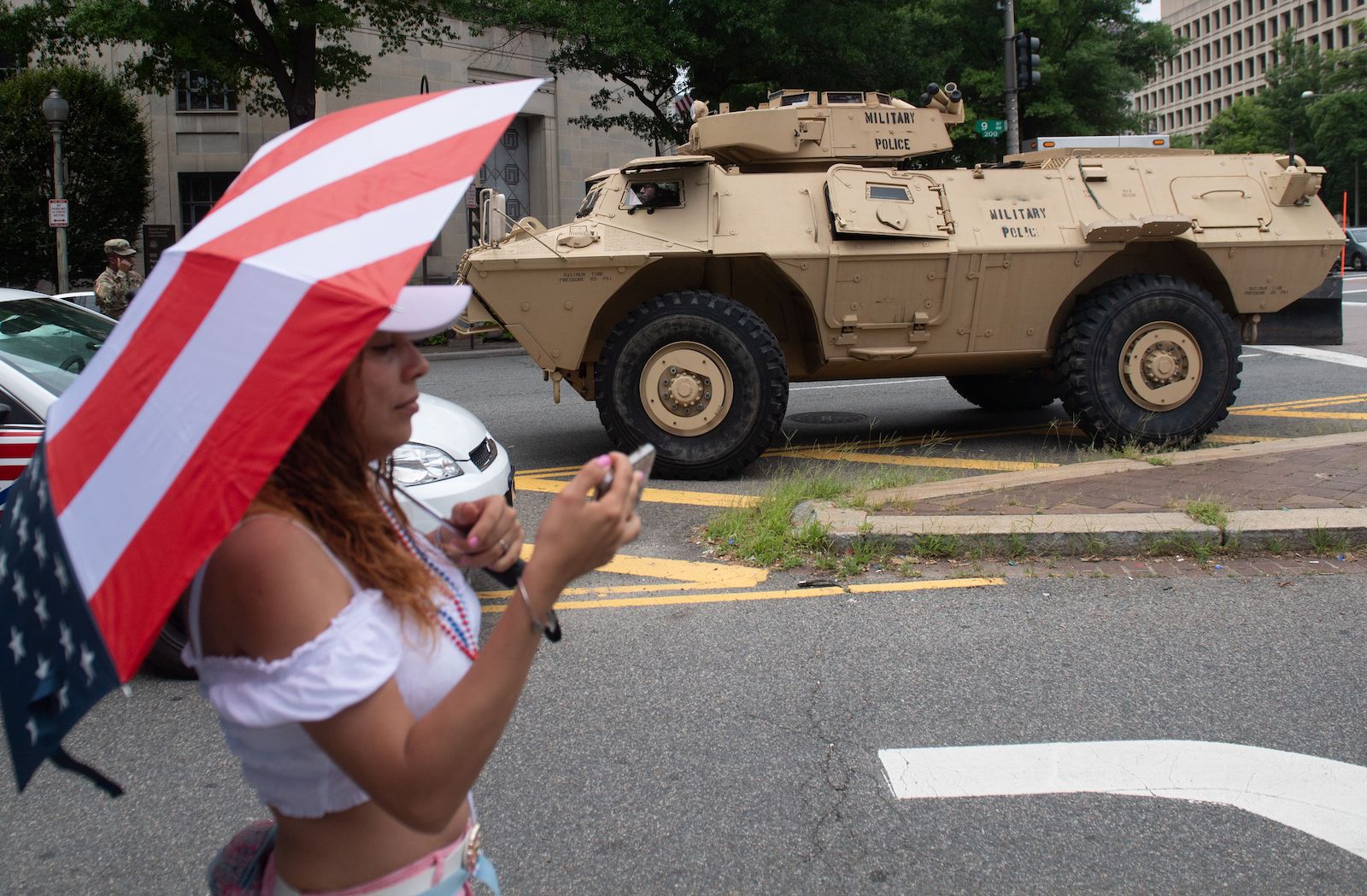 1033 program: A woman takes a photo near an armored military vehicle in Washington, DC.