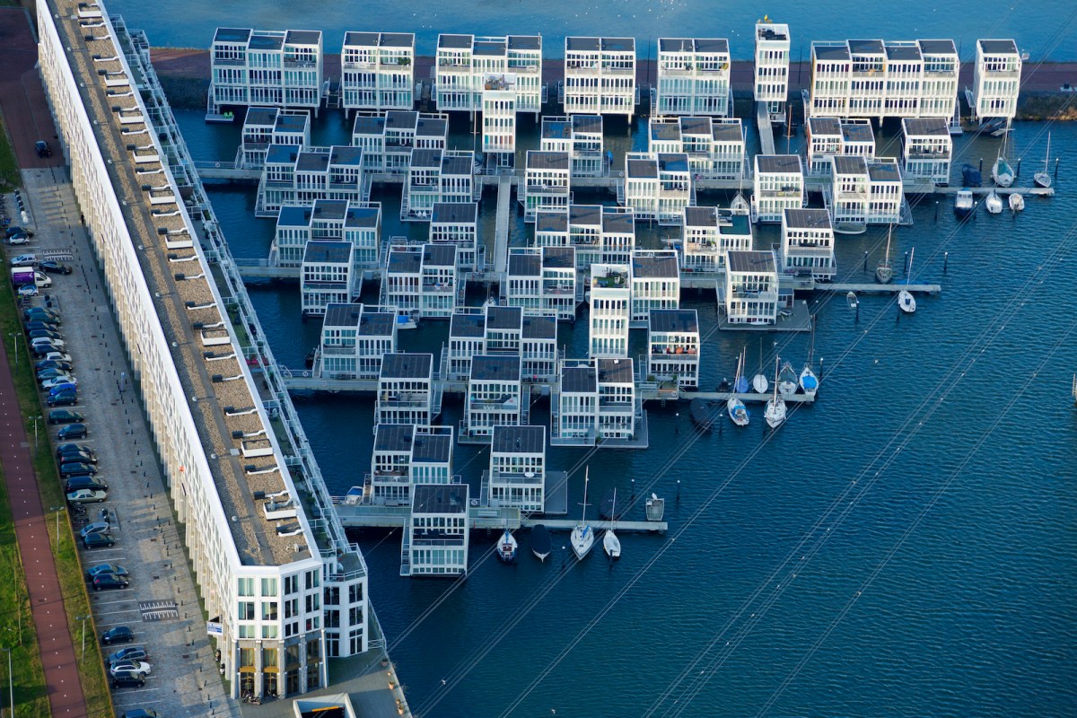 A floating community in the Netherlands lies on the coast in the IJburg section of Amsterdam. The houses are secured to large steel pilings with rolling collars that allow them to rise and fall with the water level, and sway slightly in strong winds. Each home has a small dock, communal walkways, and flexible utility connections. They are also required to be in balance, with heavy components, like kitchens and bathrooms positioned carefully on the lower floors for stability.
