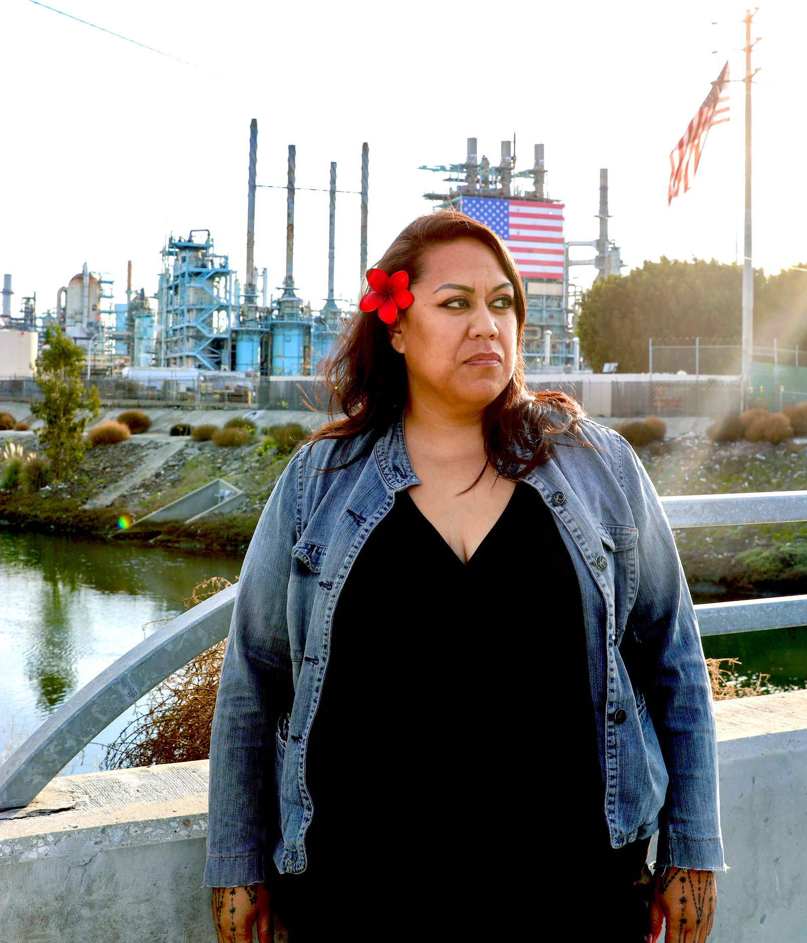Ana Meni stands in front of the Marathon Refinery on the banks of the Dominguez Channel in Carson, California.