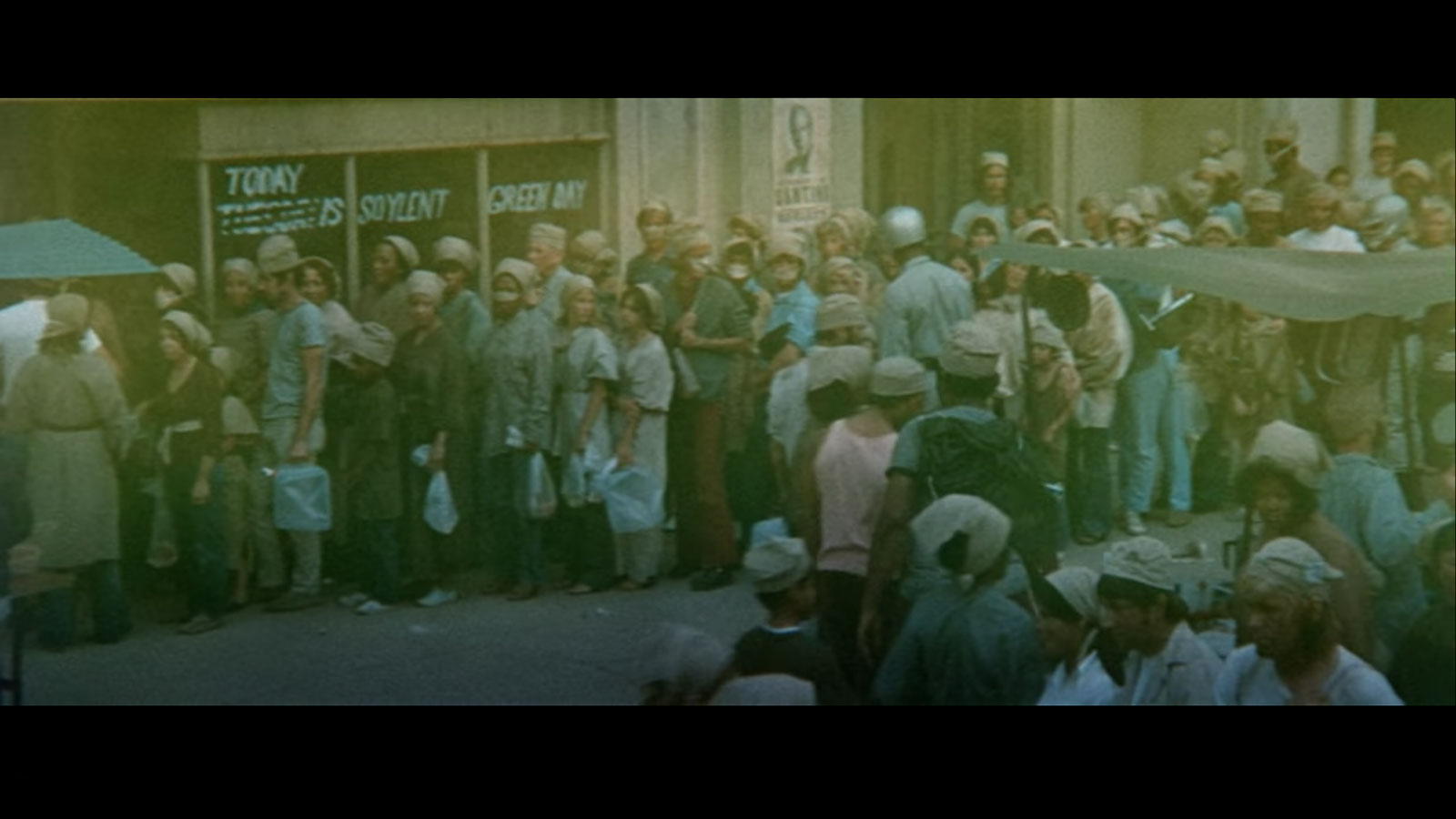 From the film Soylent Green: crowd of people waiting outside storefront reading "Today is soylent green day"
