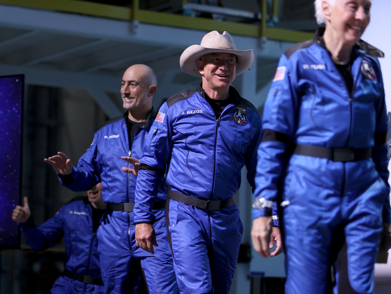 a line of people in blue jumpsuits and the center man has a white cowboy hat