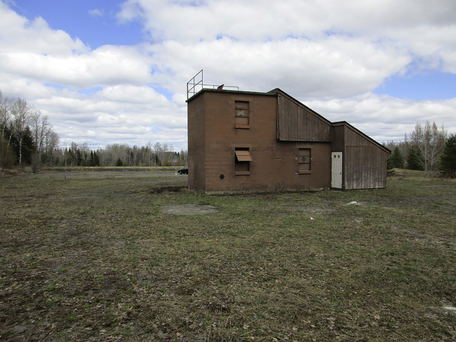 A brown building sits in empty grass field.