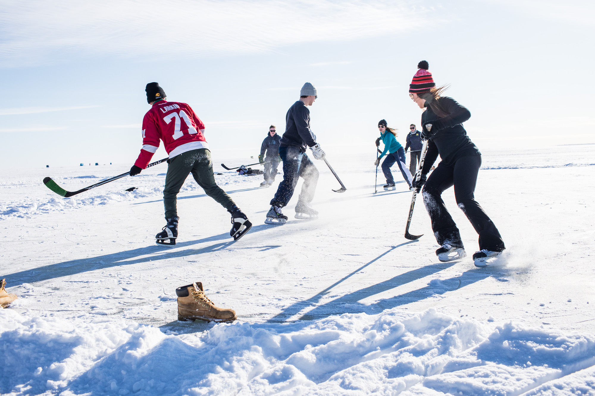 a group of young people on skates and holding hockey sticks stand on white ice and snow