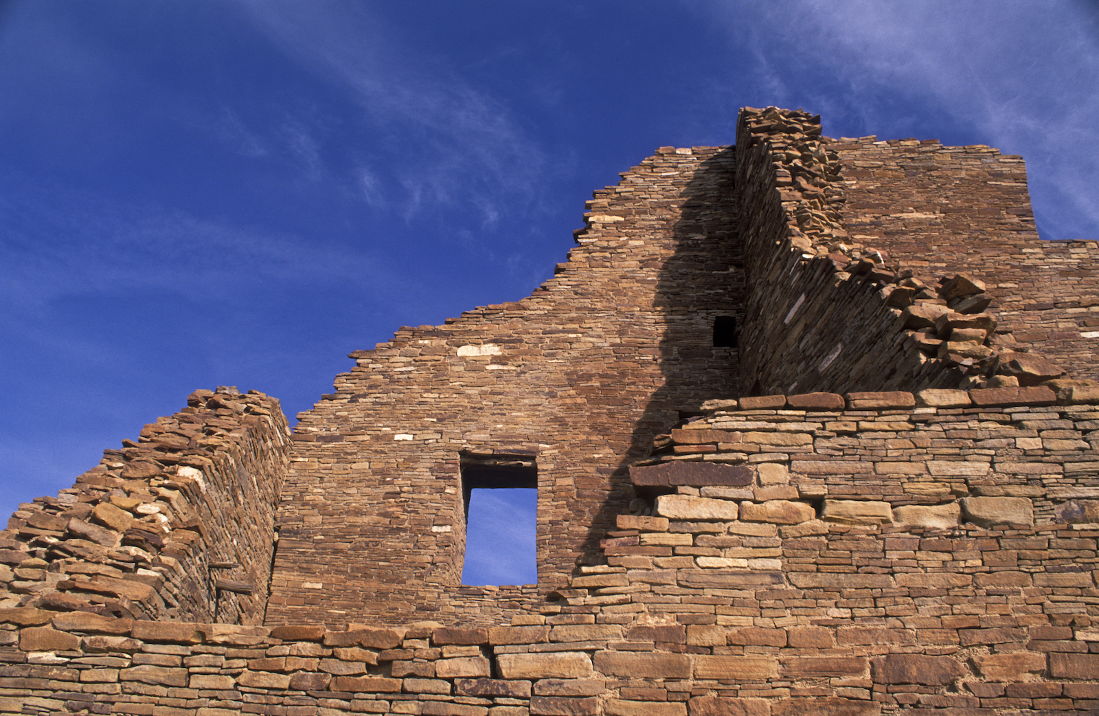blue skies and a red-brown stone structure with a window set in the center