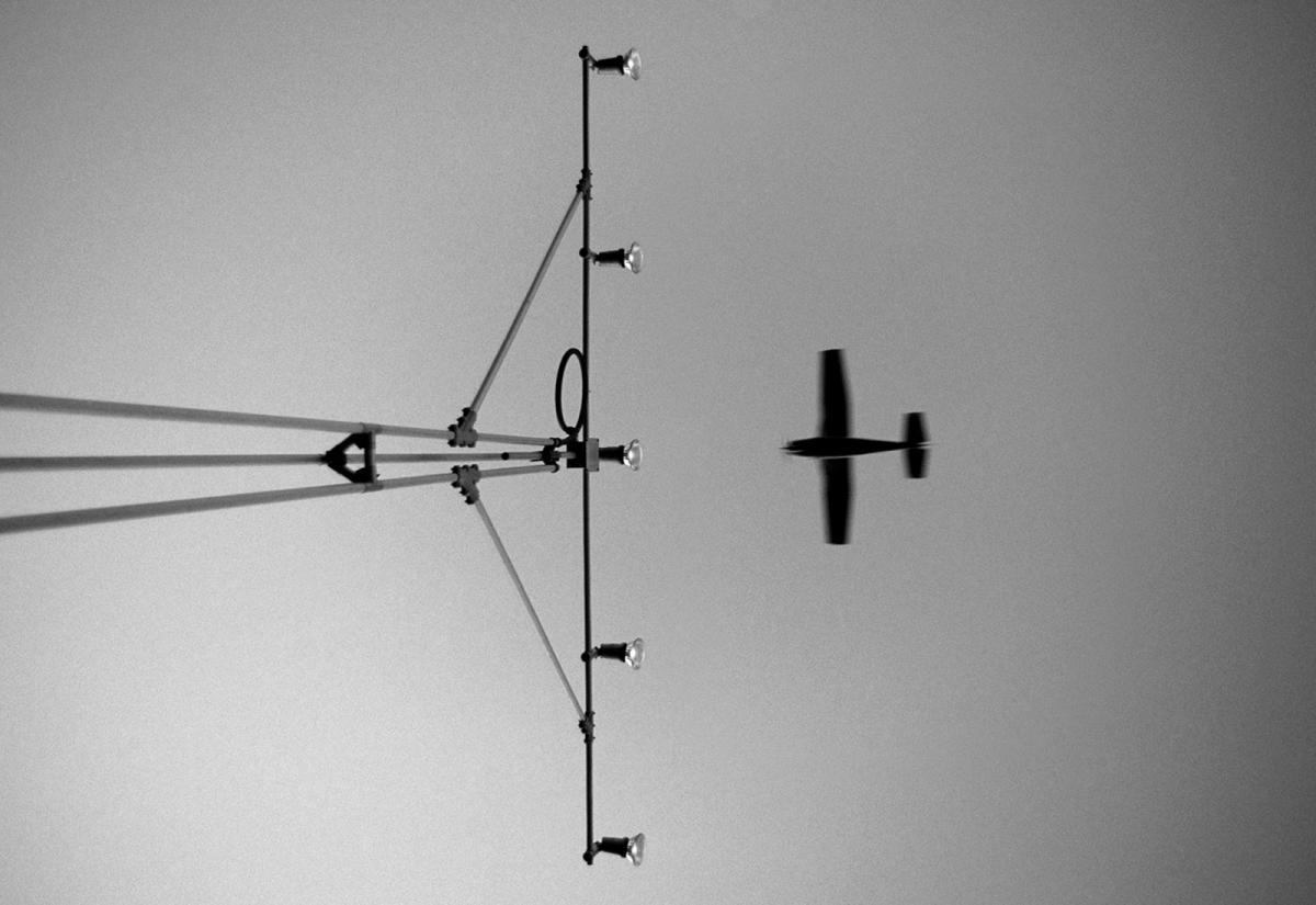 Black silhouette of small plane flying towards airport lights