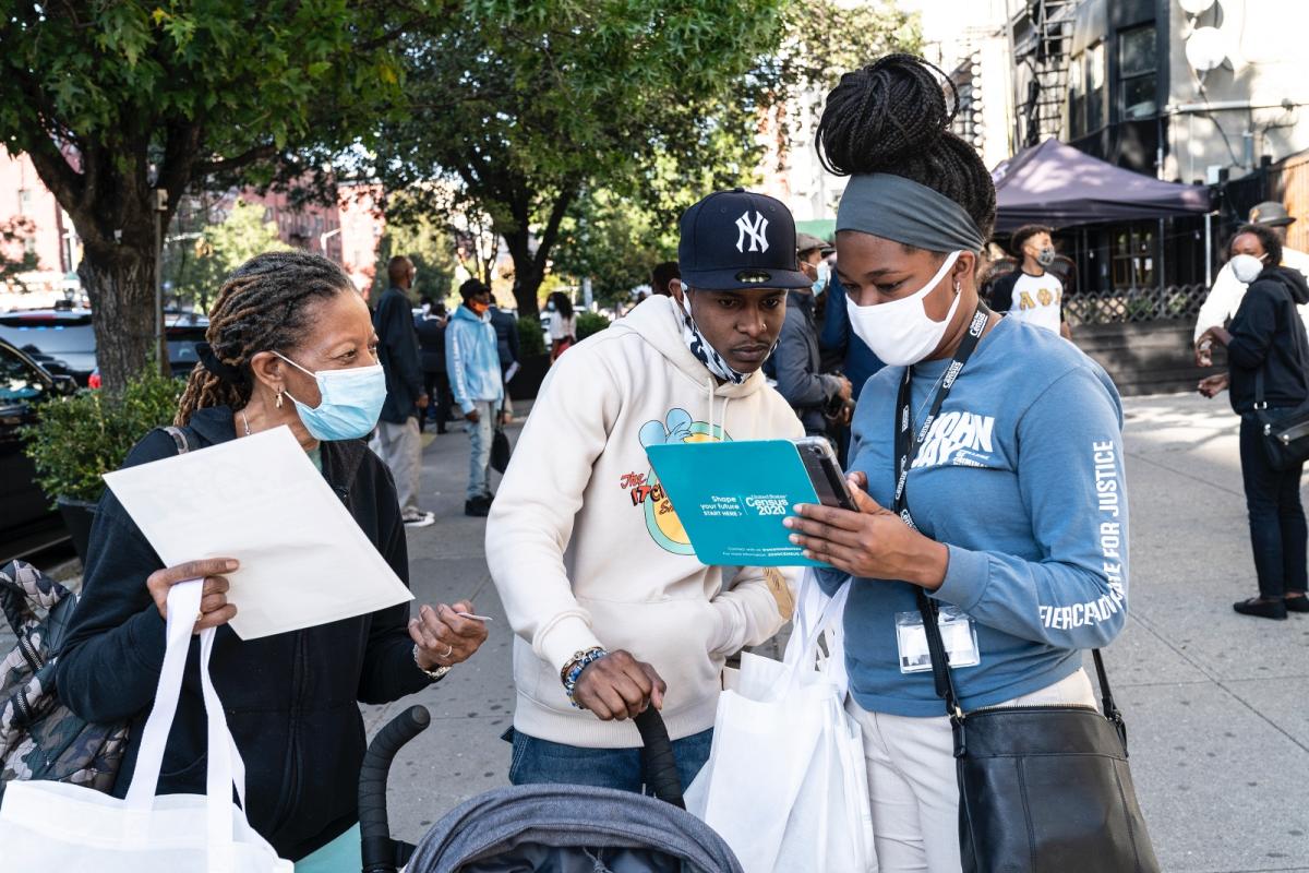 Three people look at a tablet that reads “Census 2020"