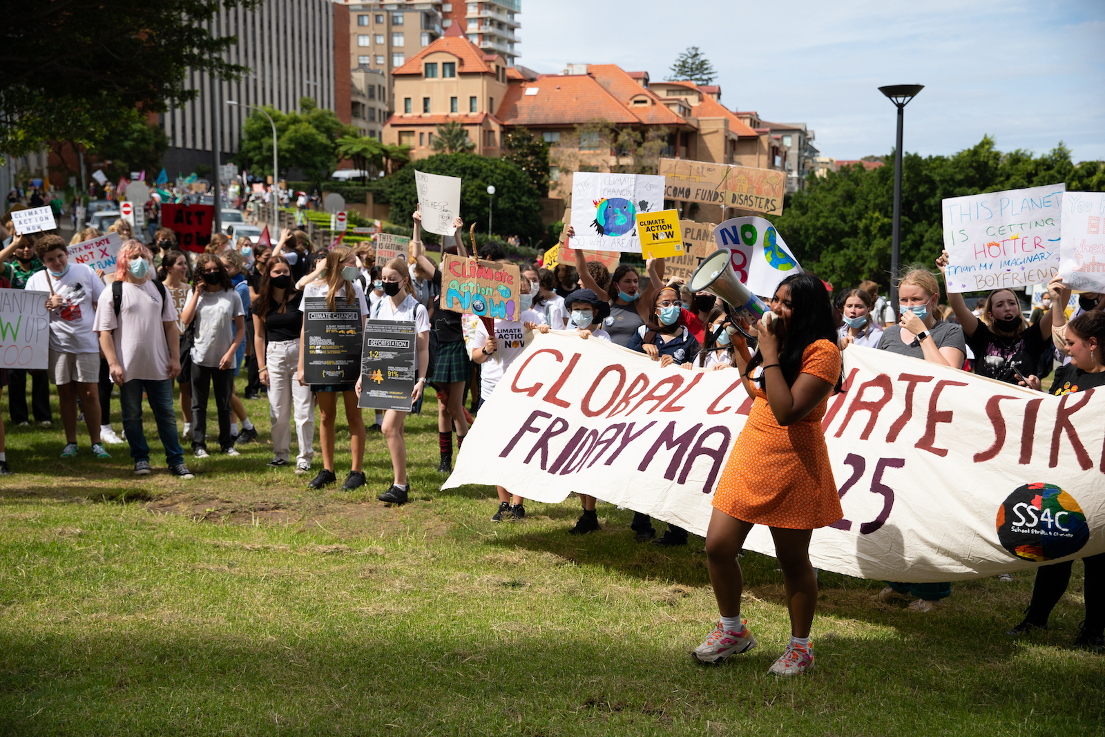 A girl holds a megaphone in front of a crowd with signs and banners