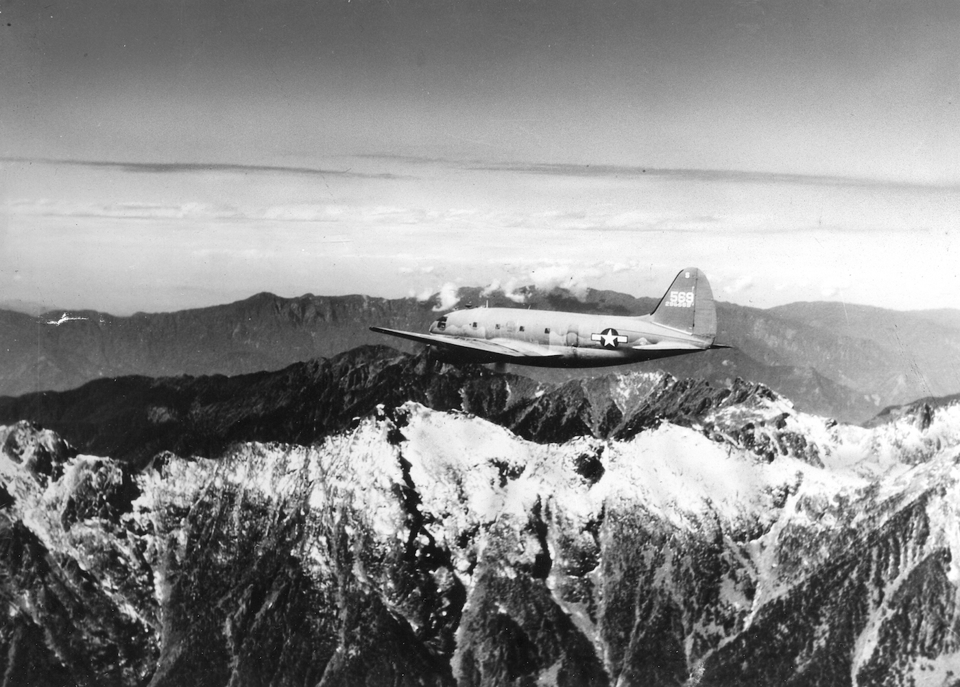 View of a US Army Air Transport Command cargo plane as it flies over the snow-capped, towering mountains of the Himalayas, along the borders of India, China, and Burma.