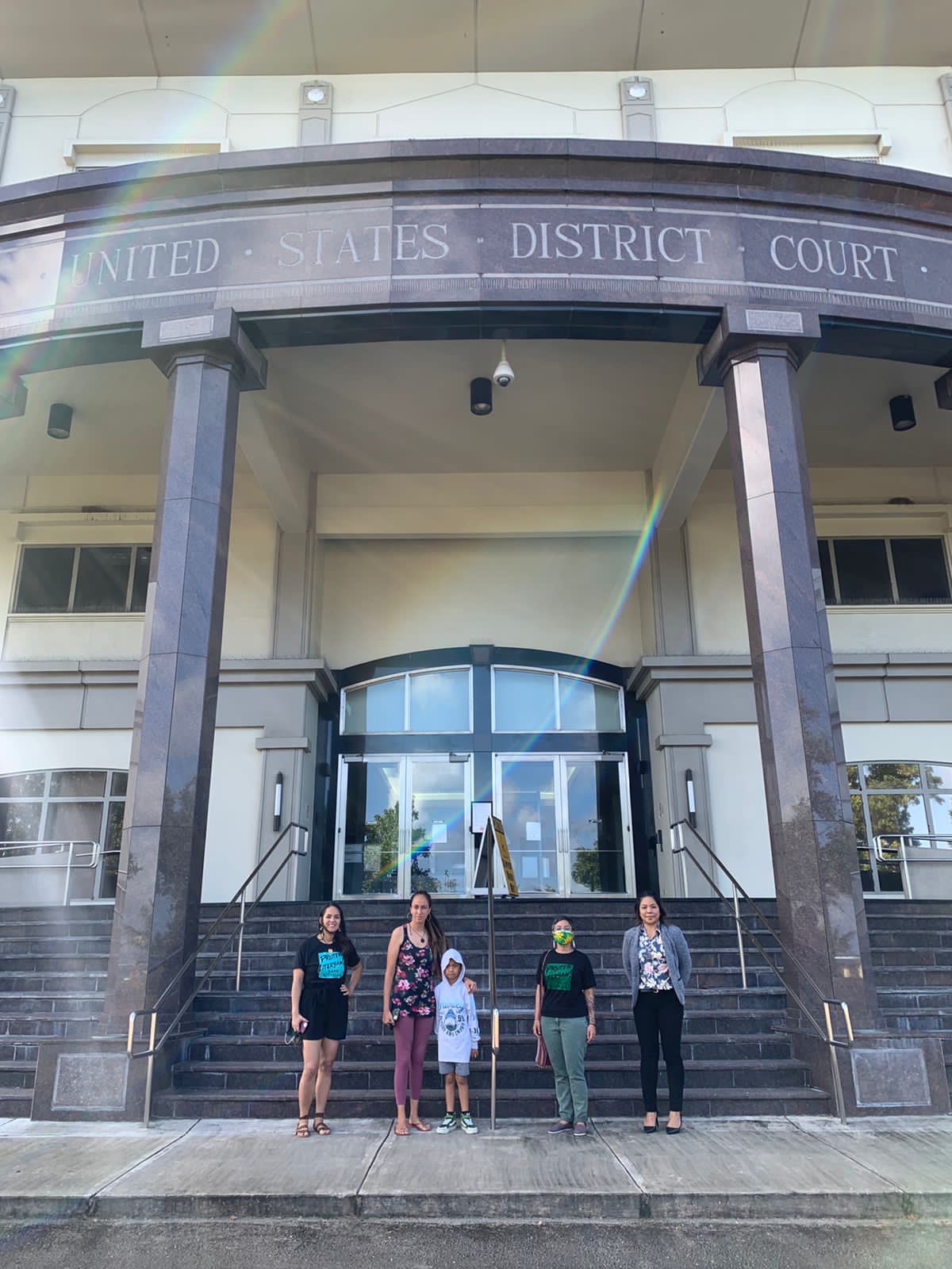 Five people stand in front of a building with the words "United States District Court" above