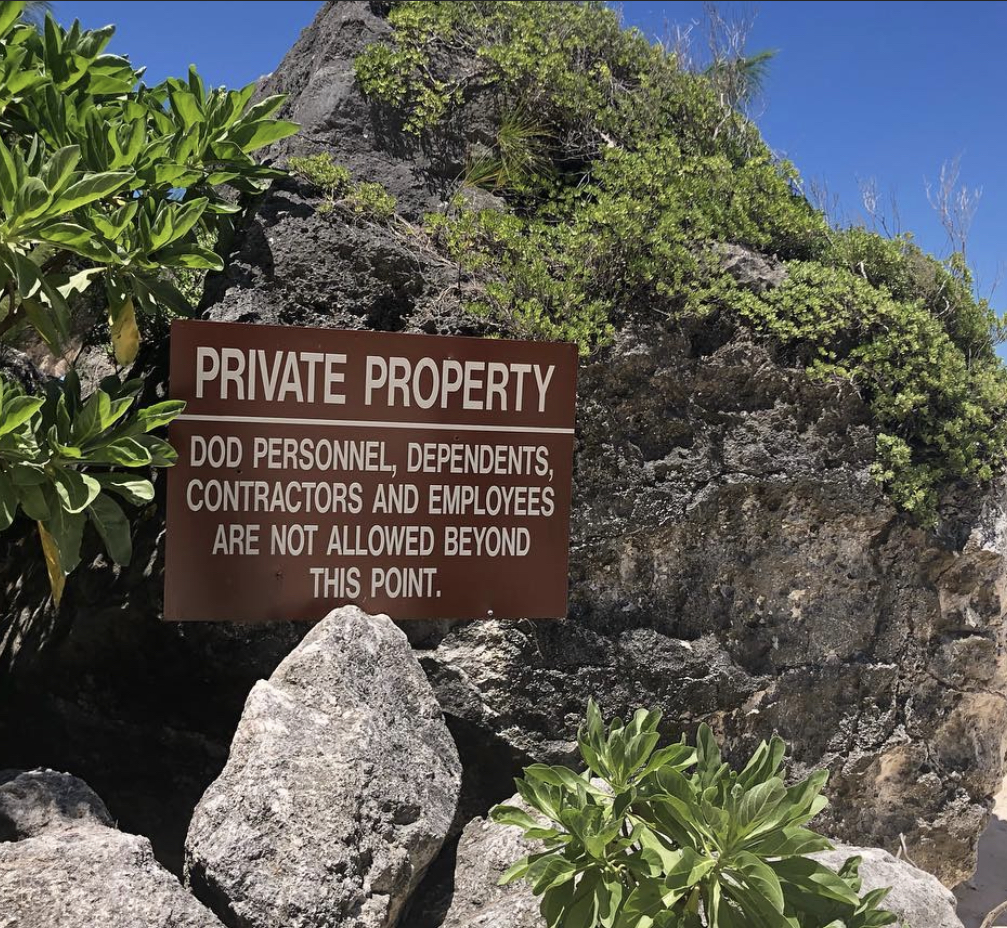 A brown sign reads: "Private property; DoD personnel, dependents, contractors and employees are not allowed beyond this point."