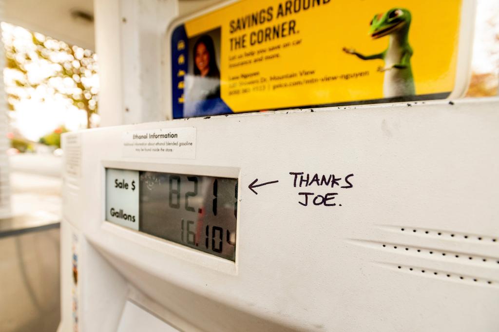 a white gas pump with a hand-drawn message in black pen saying 