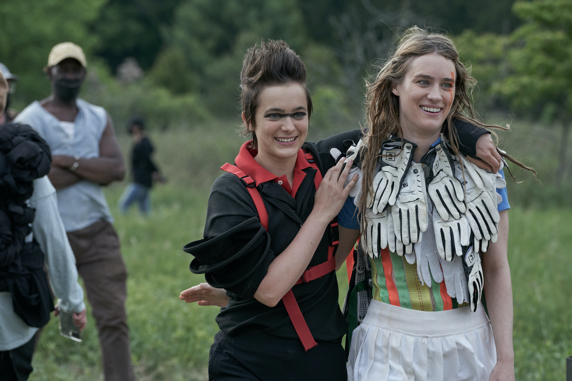 Two girls, strangely dressed, walking in a field
