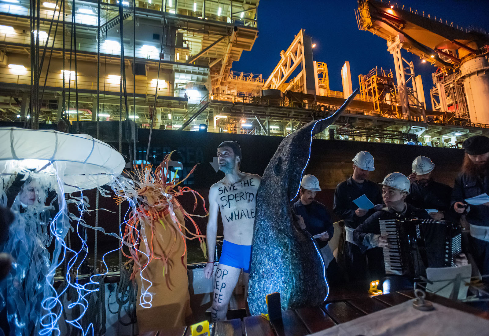 group of people, some wearing sea creature costumes, protesting in front of large deep sea mining ship